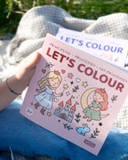 Battaniye üzerinde elde tutulan Let's Colour Princesses kitabının kapağı